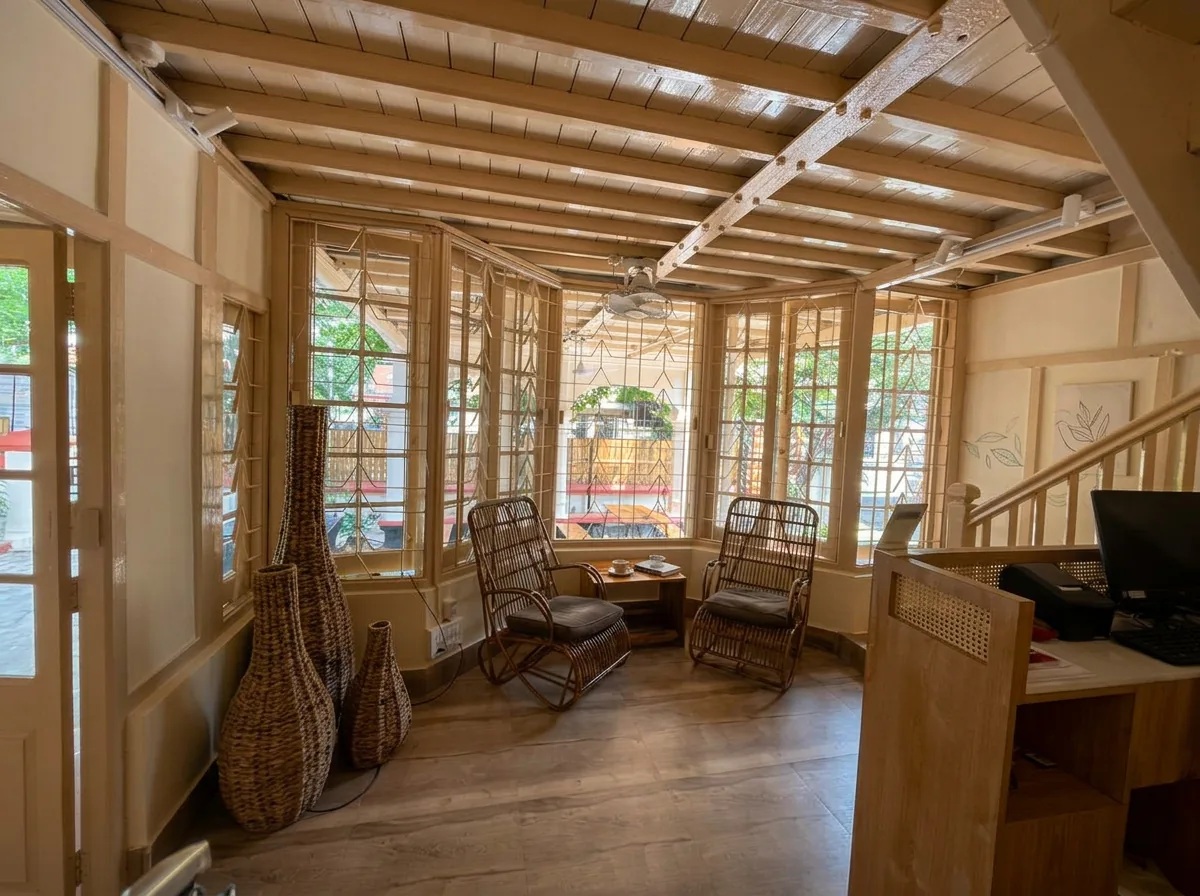 Sunroom lounge beside the reception desk, with rattan rocking chairs framed by leaded-glass windows